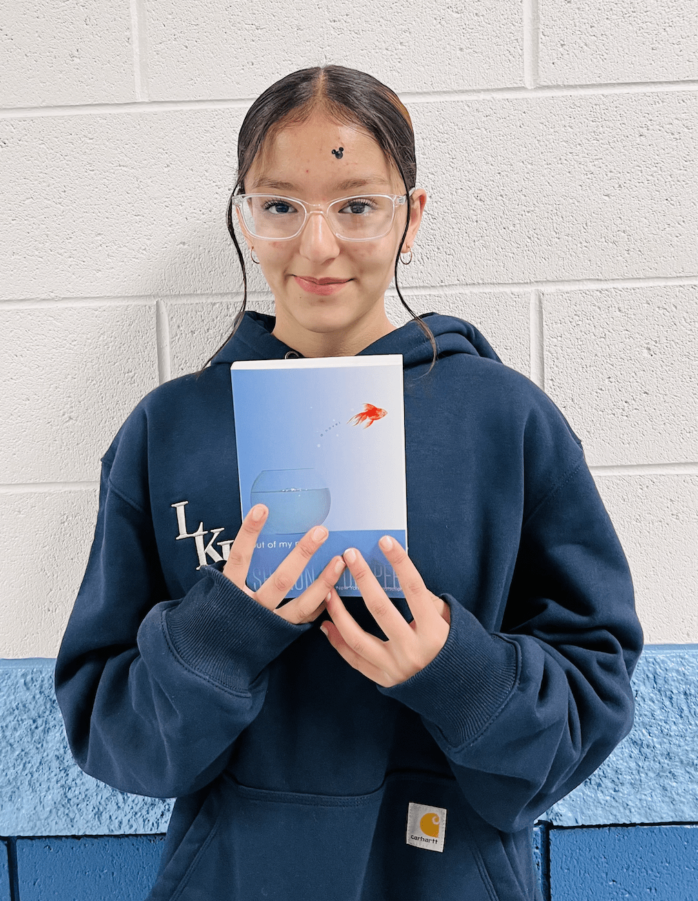 student holding a book received for earning a  praise award